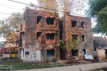 "रांची के हरमू हाउसिंग कॉलोनी में स्थित जर्जर जनता फ्लैट संख्या 11 और 12, जिसकी छतों पर पेड़ उगे हैं और खिड़की-दरवाजे टूटे हुए हैं।"