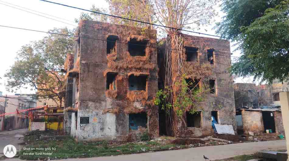 "रांची के हरमू हाउसिंग कॉलोनी में स्थित जर्जर जनता फ्लैट संख्या 11 और 12, जिसकी छतों पर पेड़ उगे हैं और खिड़की-दरवाजे टूटे हुए हैं।"